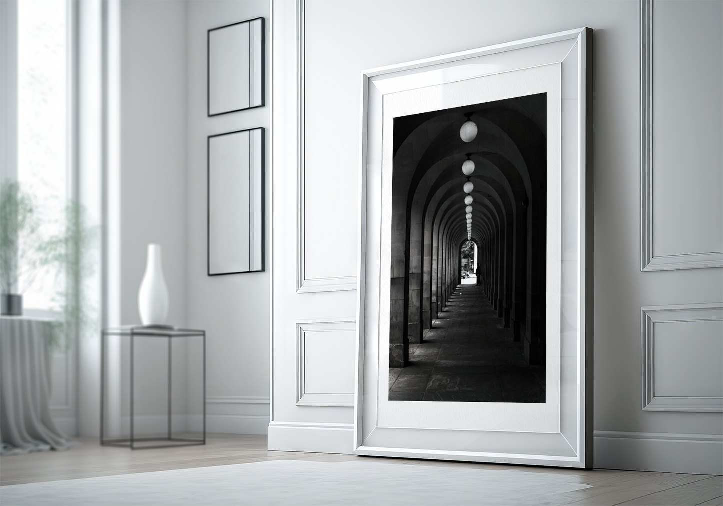 Passage, framed on a white board and a white frame. The frame is leaning against a wall, sitting on a wooden floor, in a white room lit by the sun. decorated on the wall to the left are two minimalist mirrors, and a wireframe table with a white vase. 