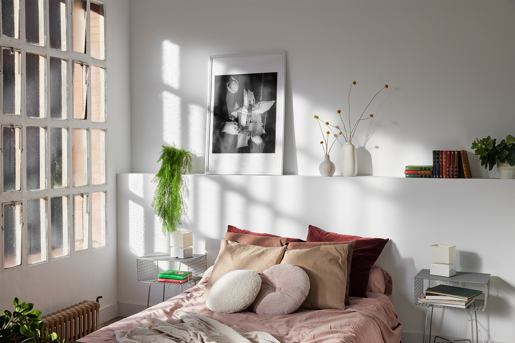 Macro print sitting at the back of a bedroom. Salmon pink bed with cushions. 