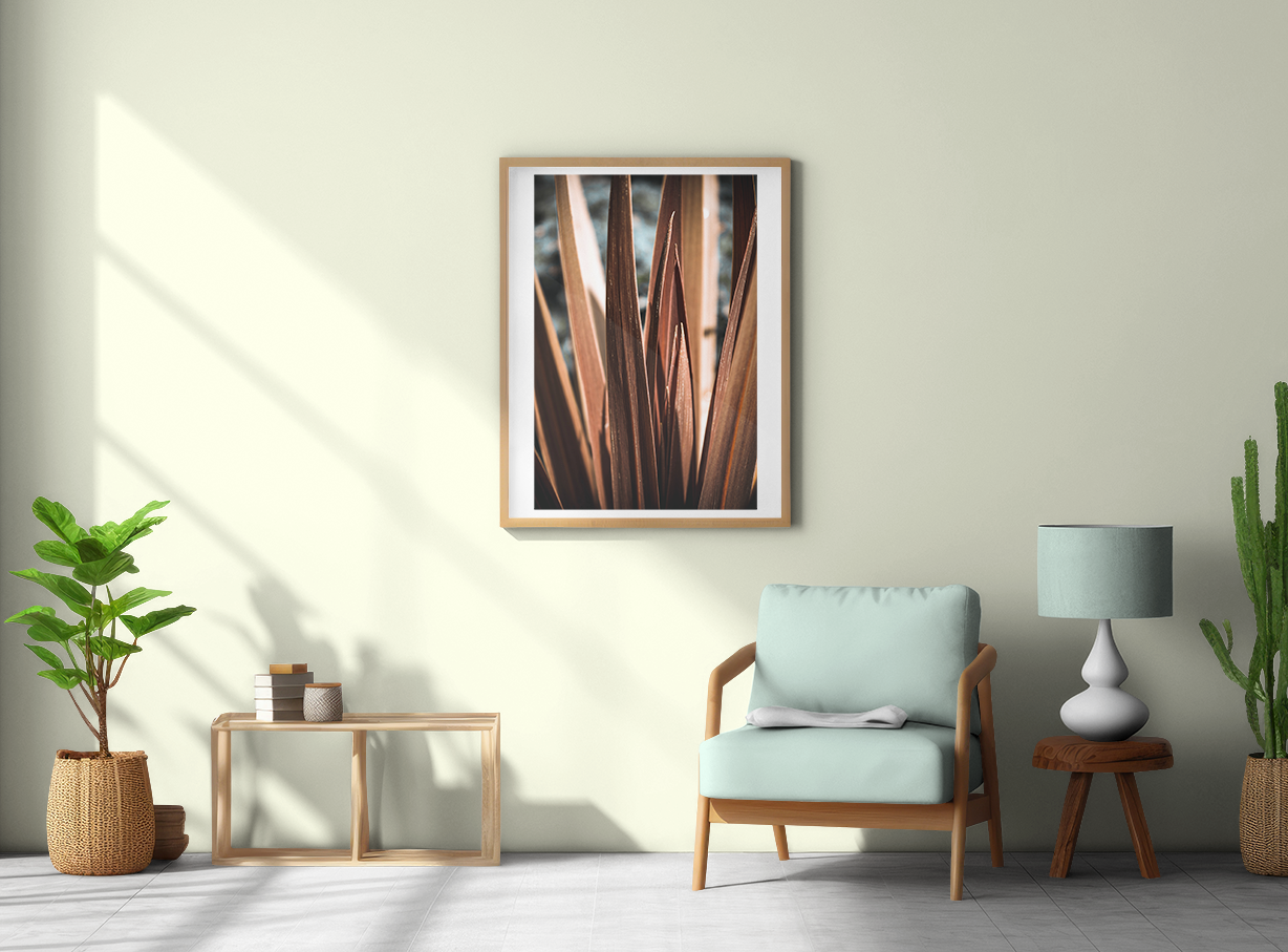 Calm abstract in a brown wood frame on white card. Placed on a pastel green wall, with a pastel room setting. natural lights comes in from the left. Plants sit in the room.