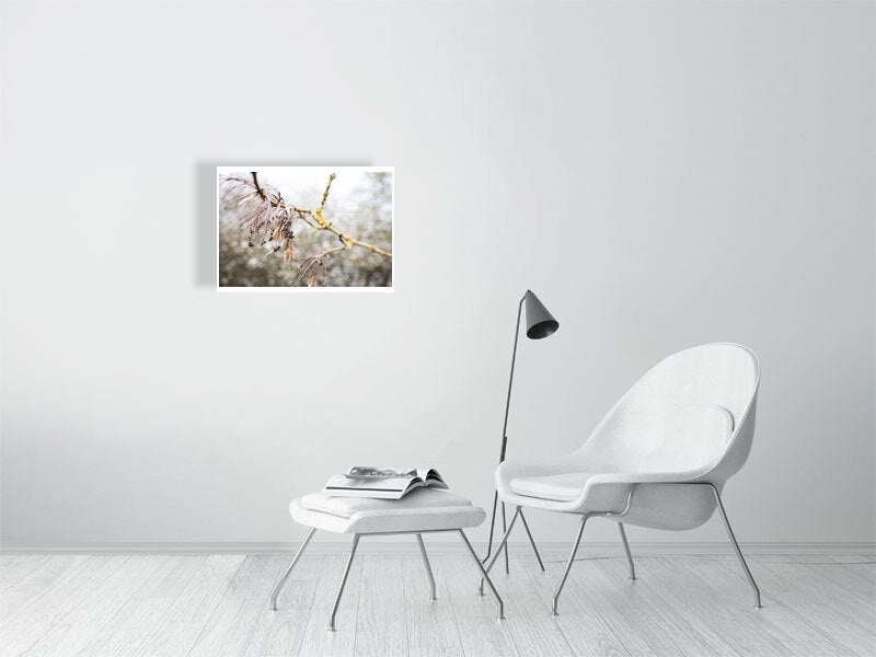 A2 print of winter's end displayed on a white wall, positioned behind and above a white living room chair. A white stool, intended for resting feet, sits nearby with a magazine/book atop it. Adjacent to the white chair stands a metal cone-shaped light fixture.