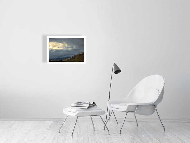 Snowdonia drama set into a minimalist white living room setting, White chair, foot stall and magazine with a small light. 