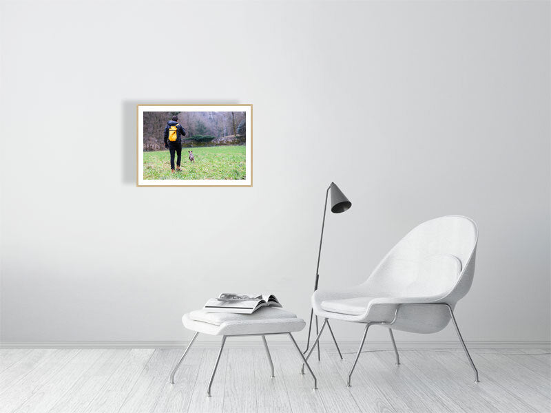 Rest days framed with a light brown frame, displayed in a white minimalist room, chair, stool with a magazine on it, a side light. 